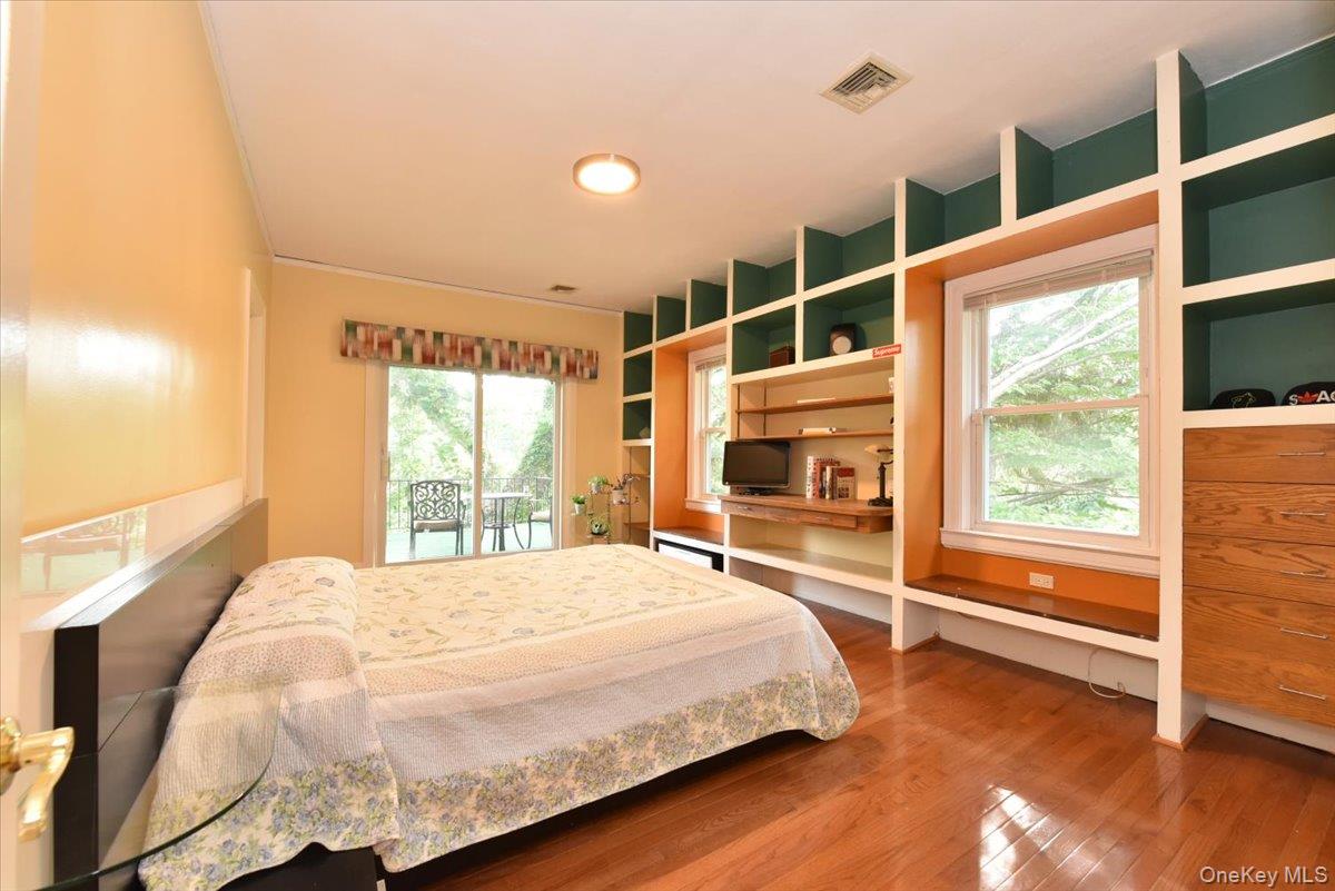 Bedroom with access to exterior, wood finished floors, and visible vents