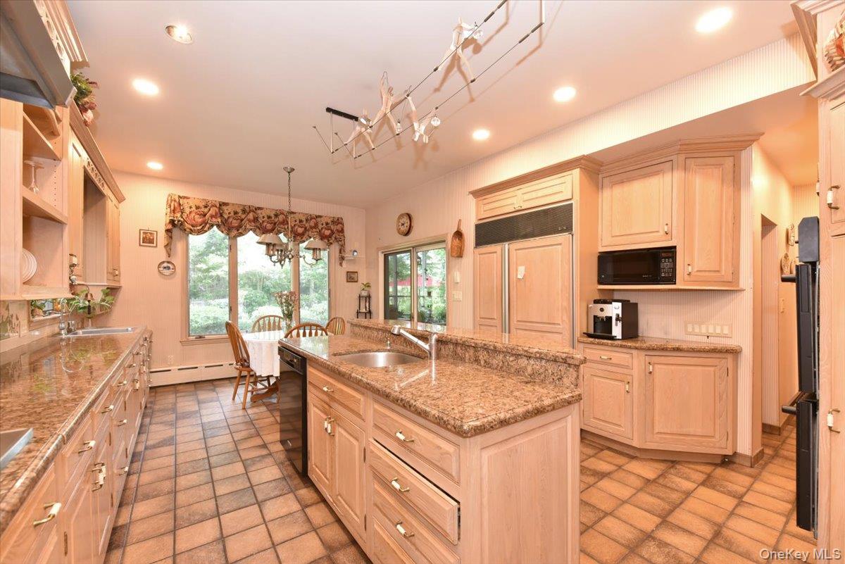 Kitchen with a sink, black appliances, recessed lighting, and an island with sink