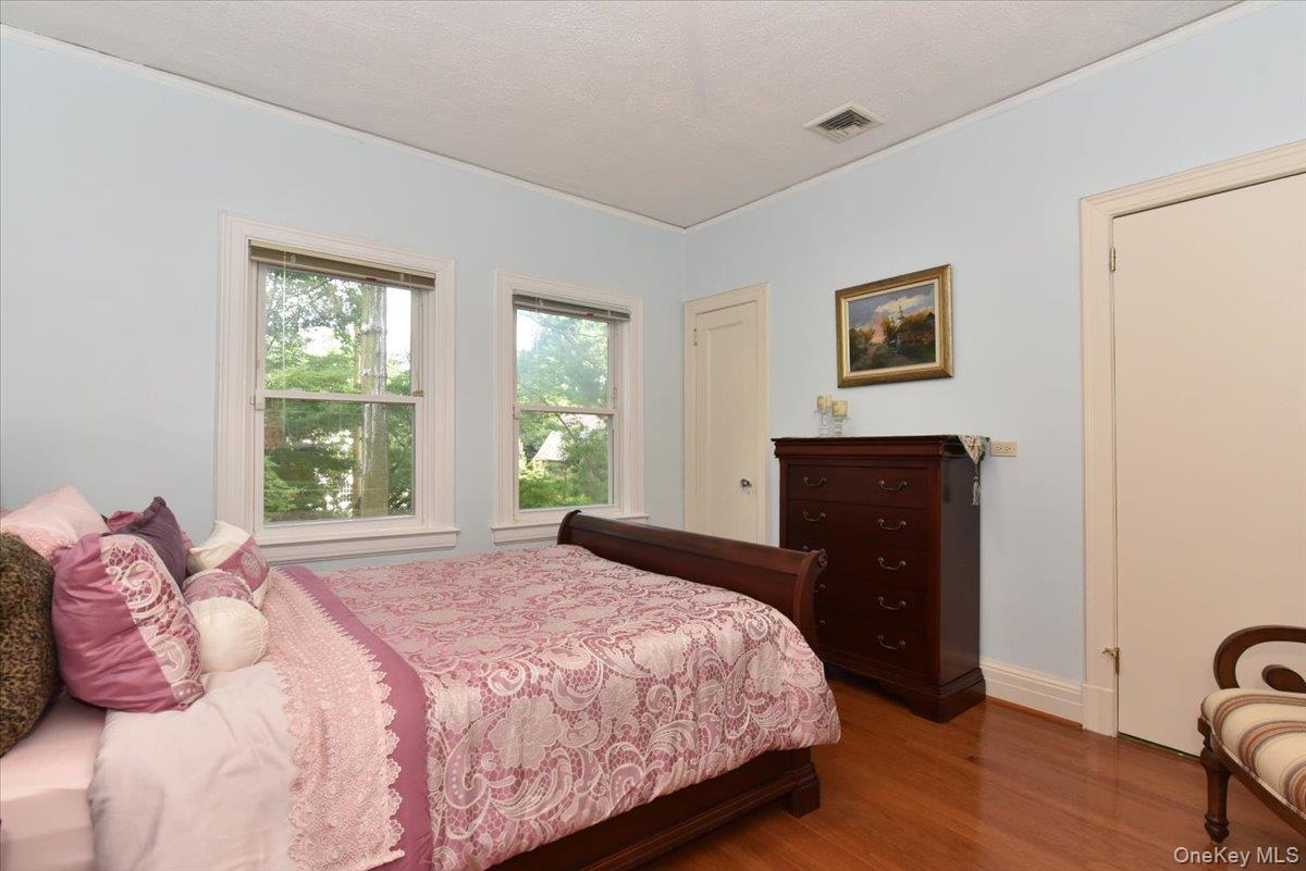 Bedroom with visible vents, baseboards, ornamental molding, and wood finished floors
