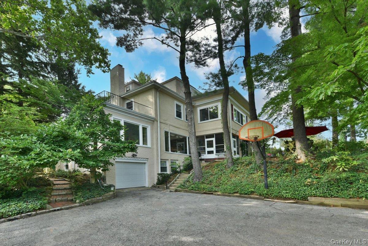 View of home's exterior featuring an attached garage, a balcony, a chimney, stucco siding, and driveway
