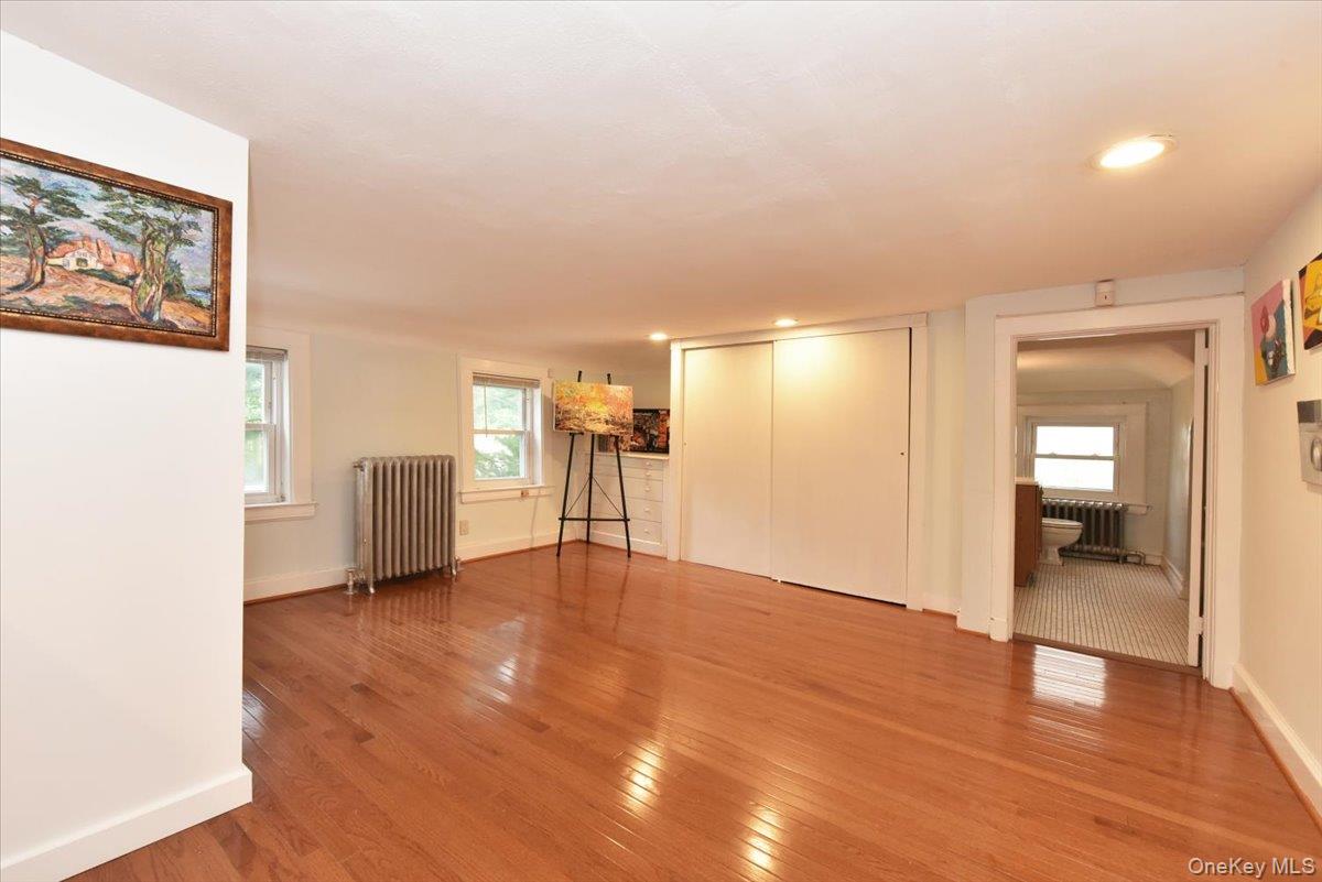 Unfurnished living room with light wood-style flooring, radiator heating unit, and baseboards