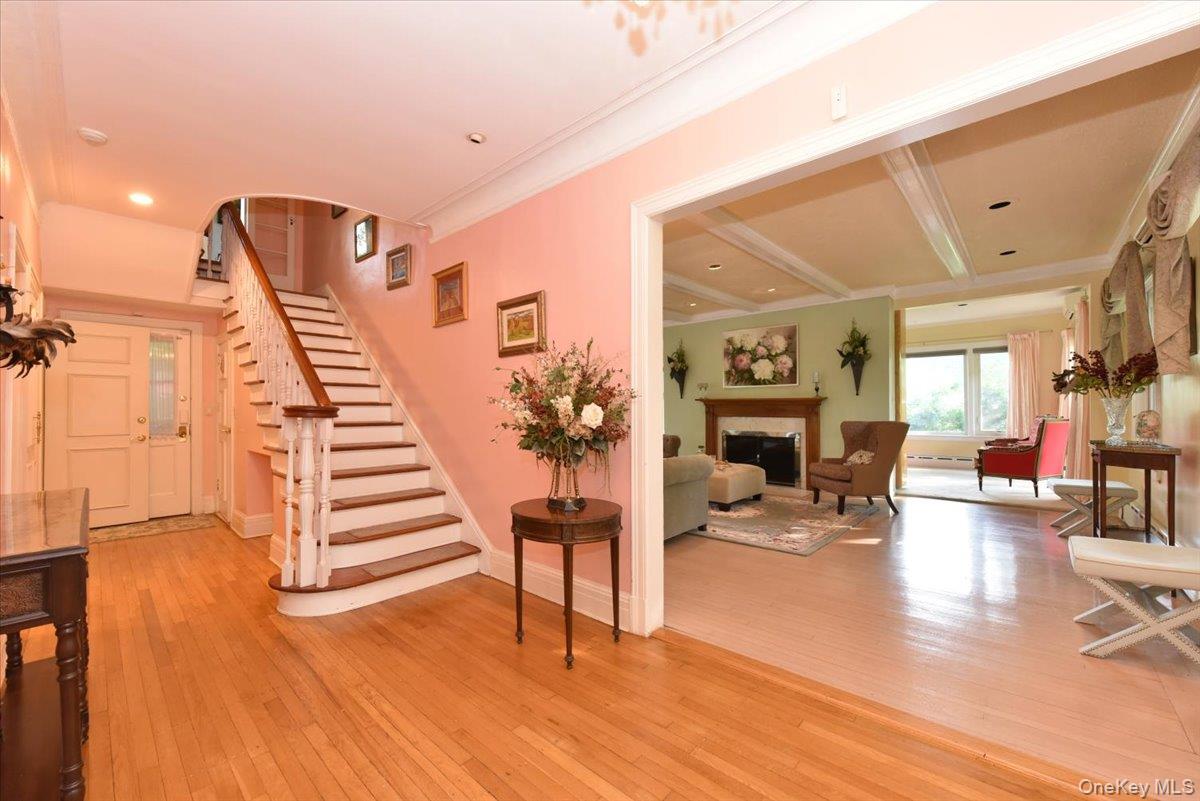 Stairway featuring baseboard heating, baseboards, a fireplace, crown molding, and hardwood / wood-style floors