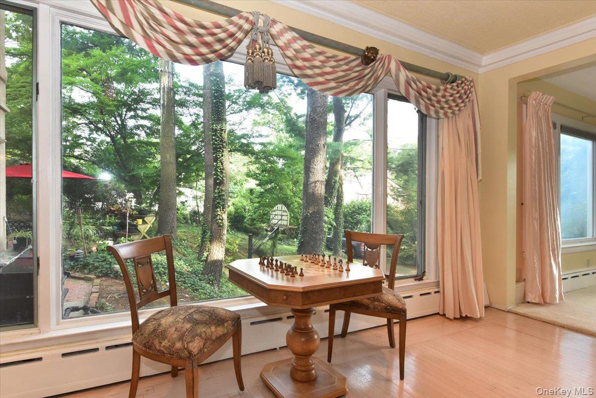 Sunroom with crown molding, a baseboard heating unit, and wood finished floors
