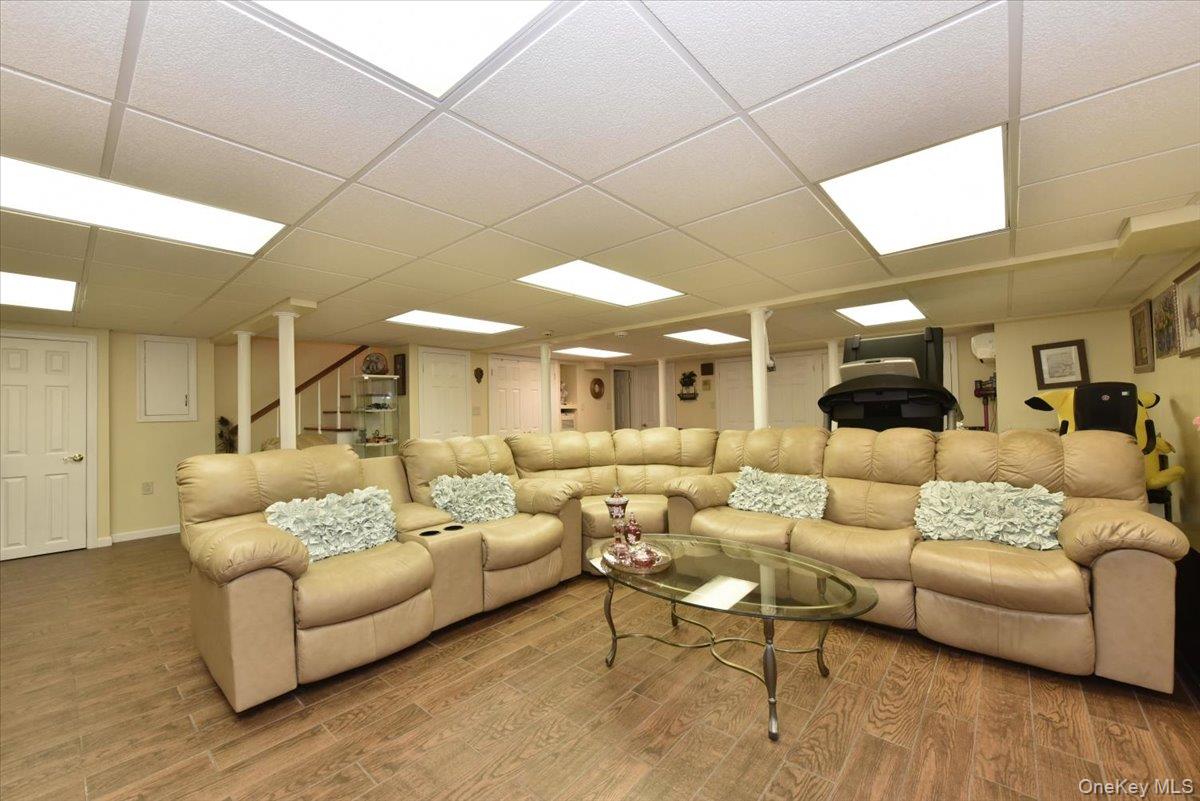 Living room featuring stairs, a drop ceiling, and wood finished floors