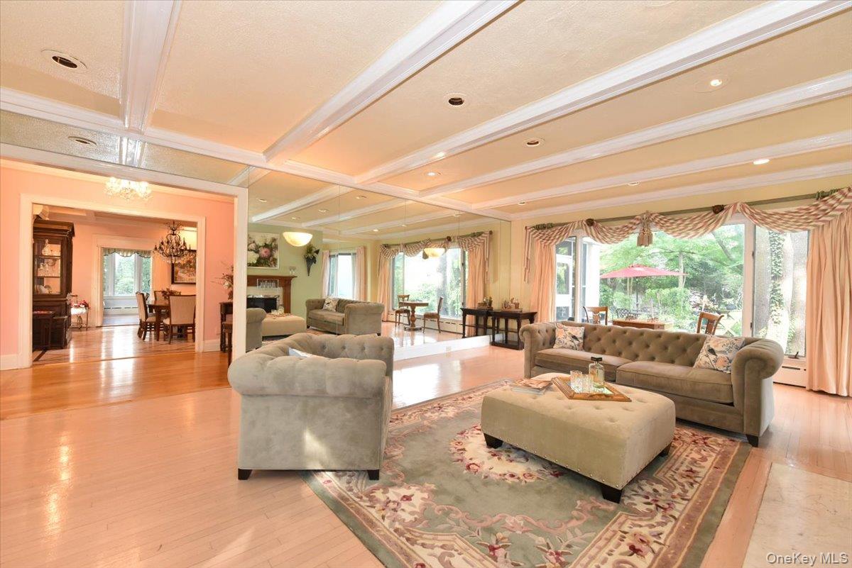 Living area with coffered ceiling, beamed ceiling, a notable chandelier, and plenty of natural light