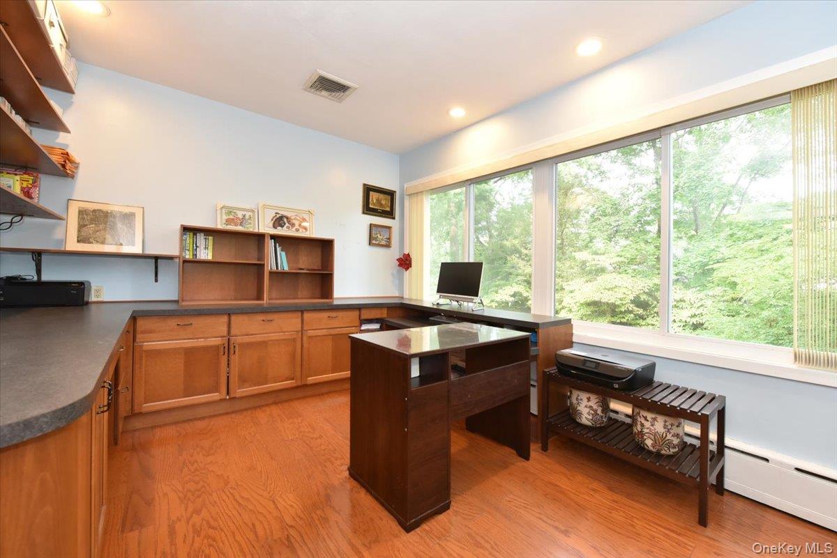 Office area with visible vents, light wood finished floors, a baseboard heating unit, and recessed lighting