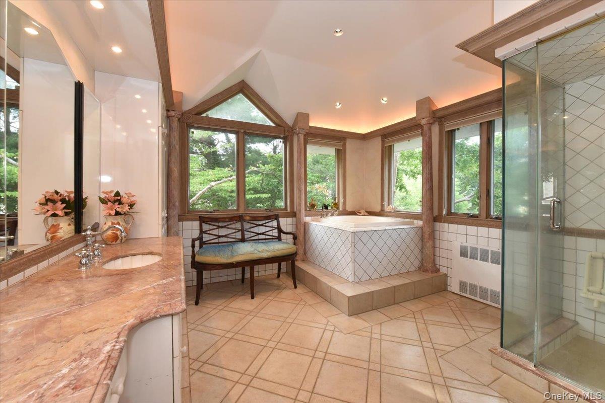 Bathroom featuring lofted ceiling, radiator heating unit, tile patterned flooring, a stall shower, and a garden tub
