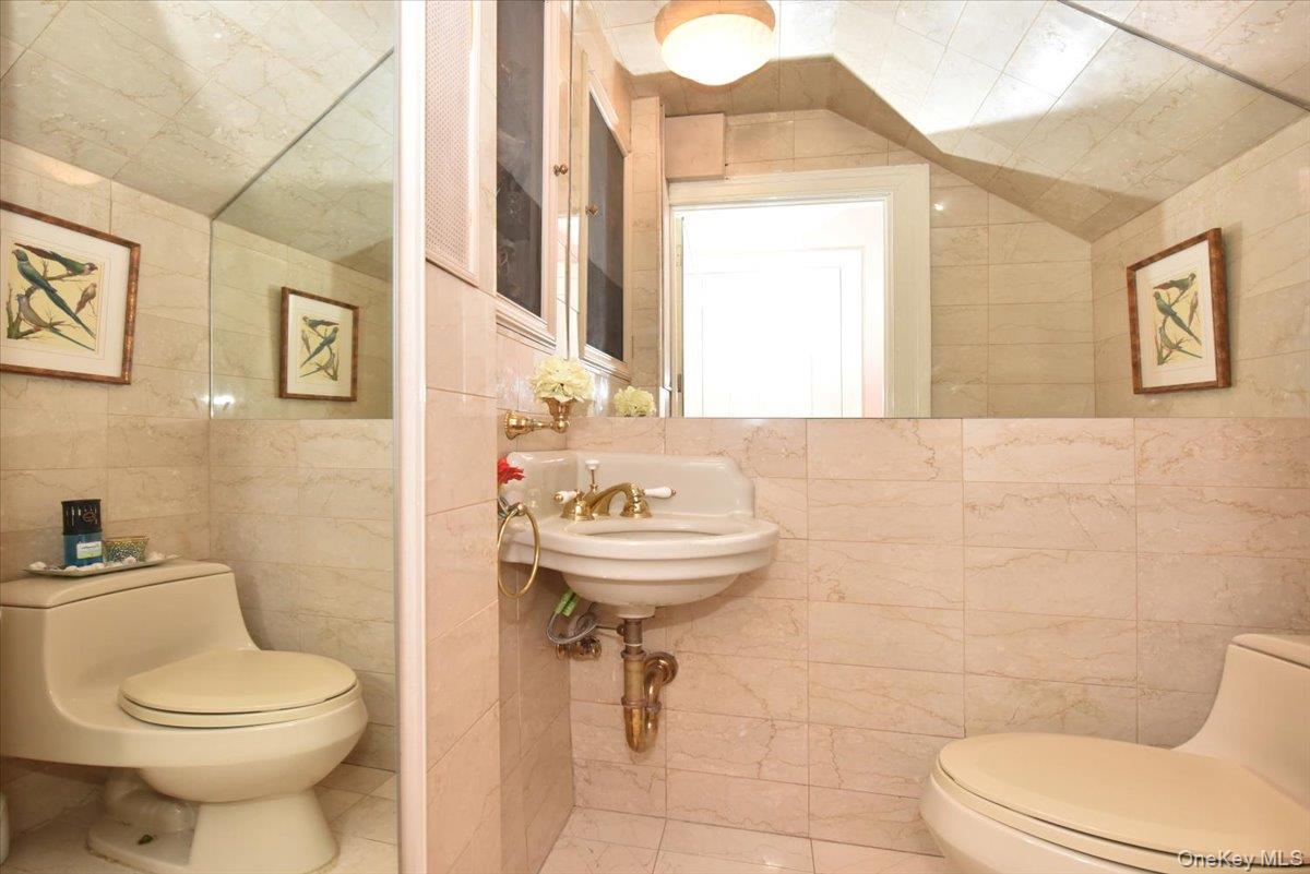 Bathroom featuring tile walls, a sink, and toilet