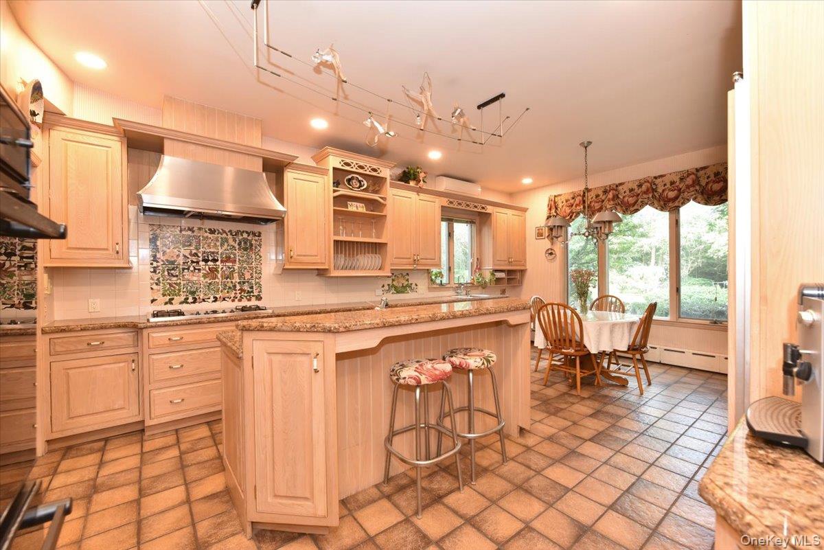 Kitchen featuring a baseboard heating unit, wall chimney range hood, recessed lighting, gas stovetop, and decorative backsplash