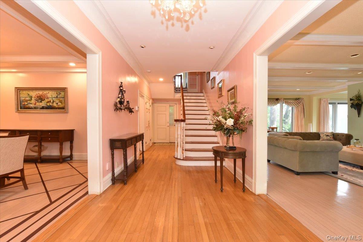 Hall featuring ornamental molding, light wood-type flooring, stairway, and baseboards