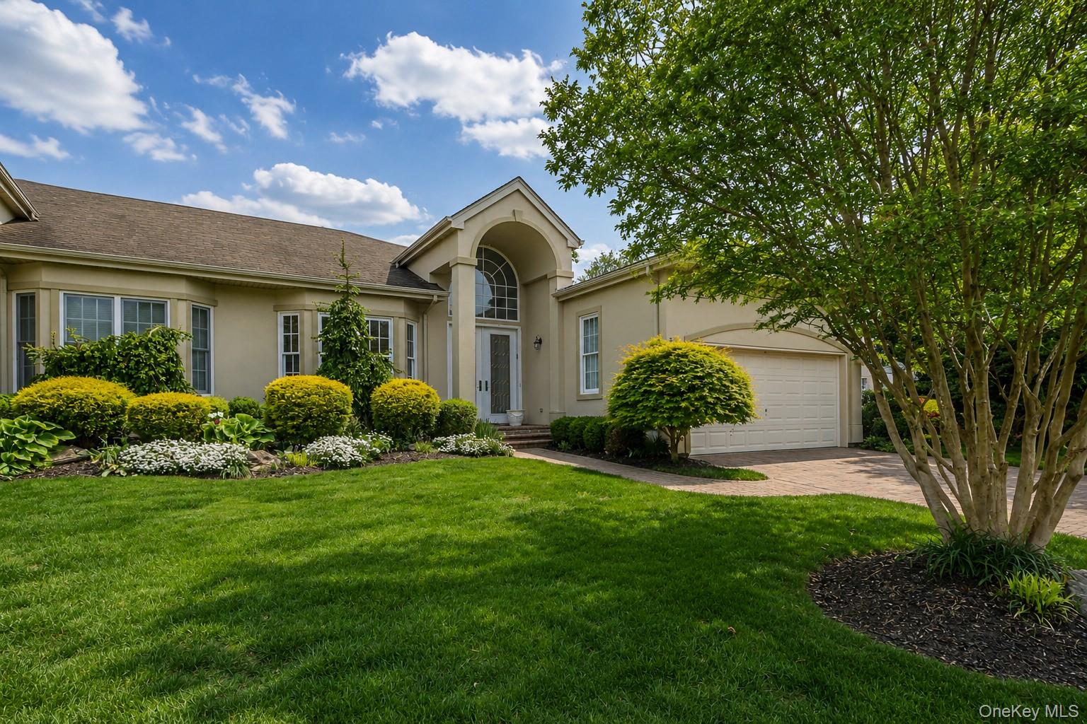 Stucco exterior with a peaked entryway featuring an arched transom window