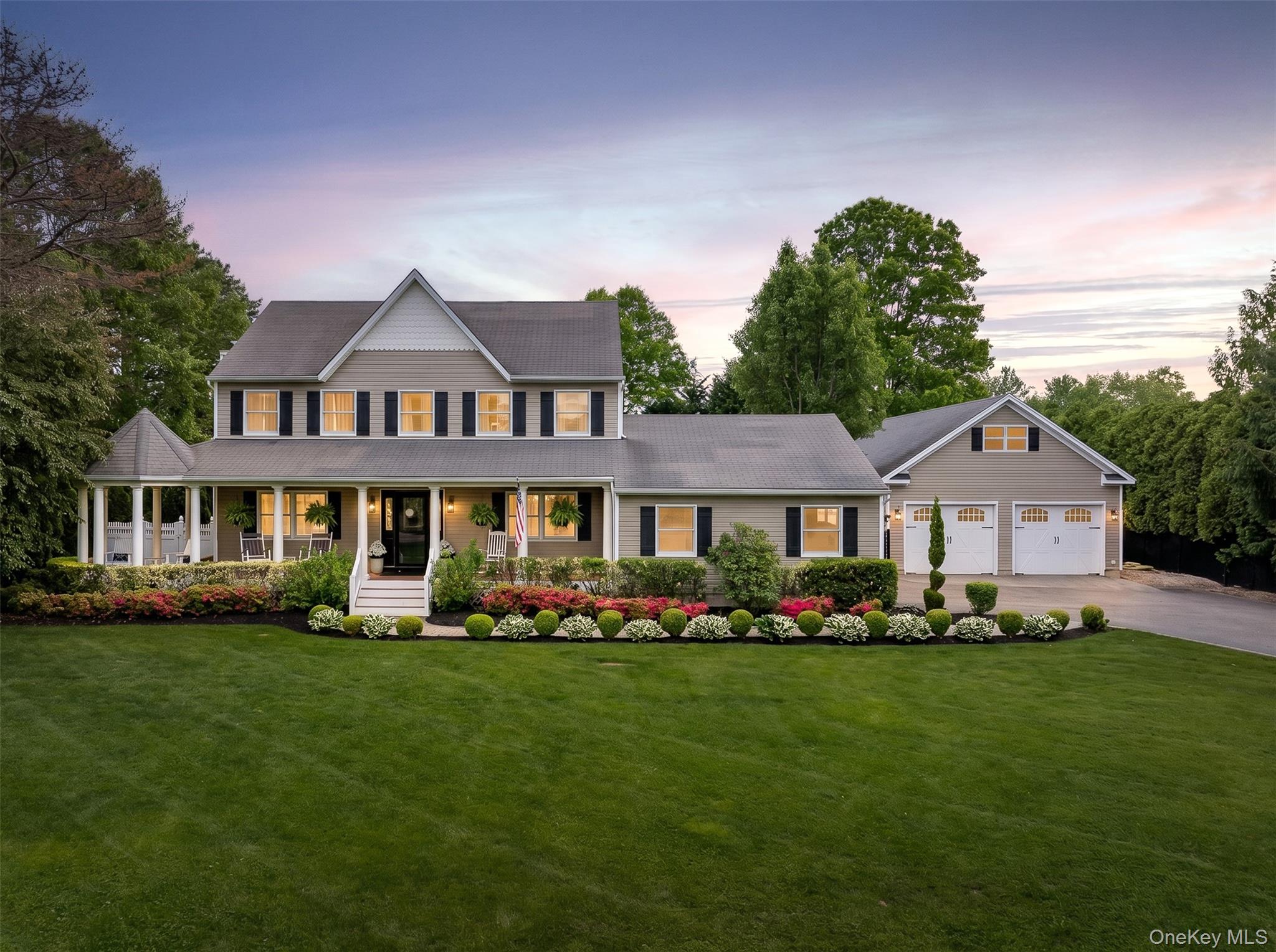 Traditional-style residence featuring a prominent front porch with a rounded gazebo extension, a dormered roofline, and an attached two-car garage
