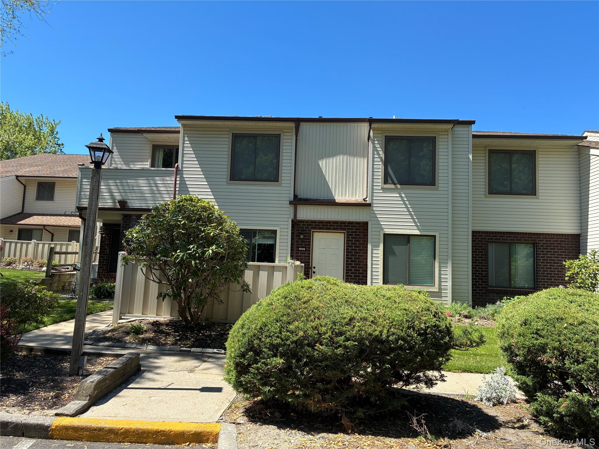 Outside front view of UPPER unit condo showing attached Balcony to the left and showing sidewalk (short walk) to Parking Lot