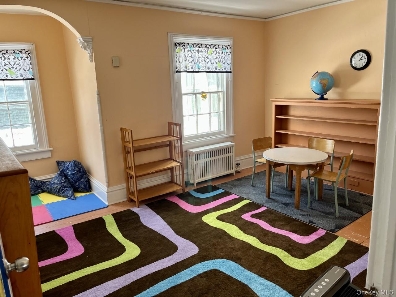 Recreation room with radiator, ornamental molding, and arched walkways