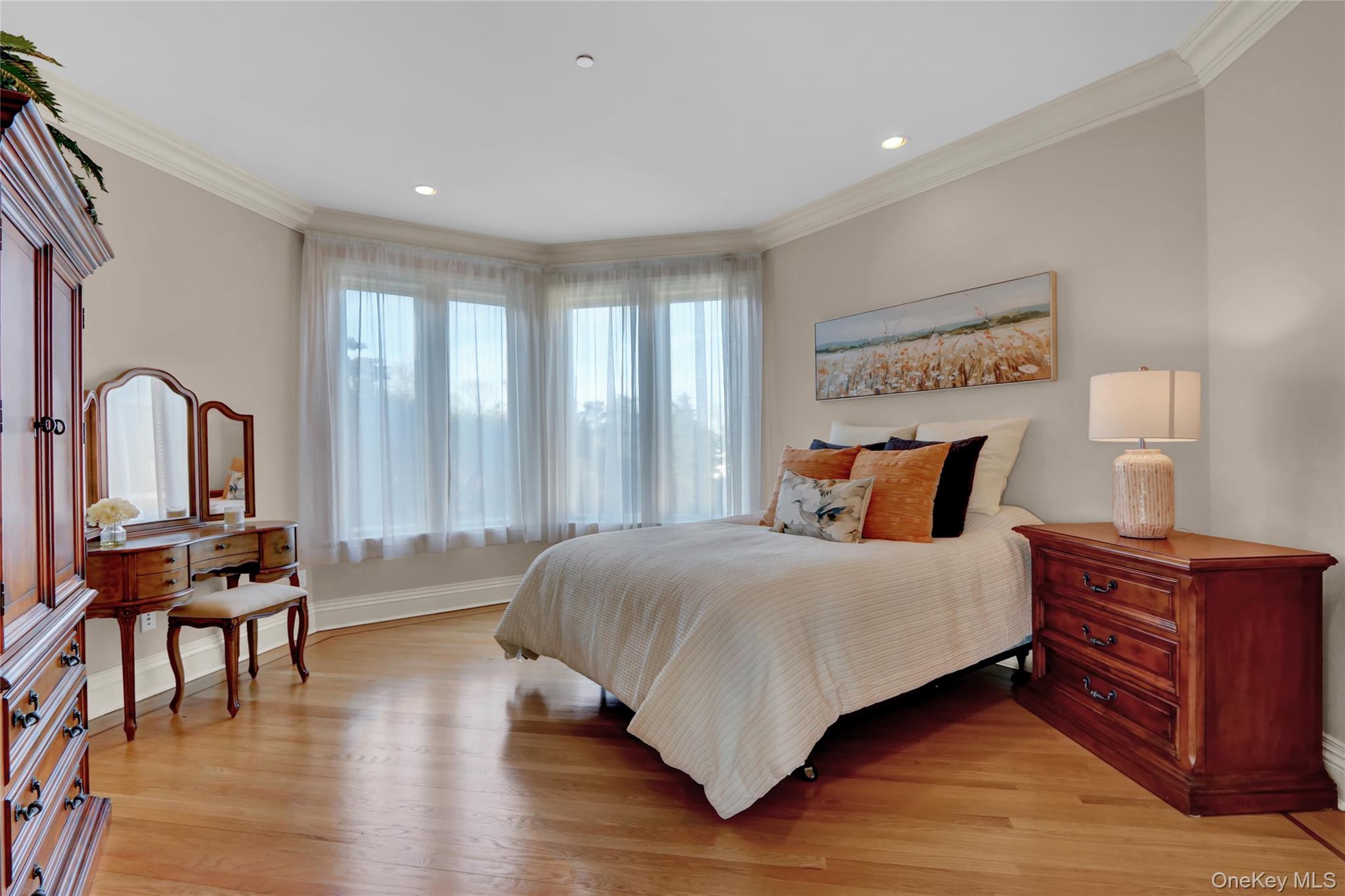 Bedroom with crown molding, light wood finished floors, and baseboards