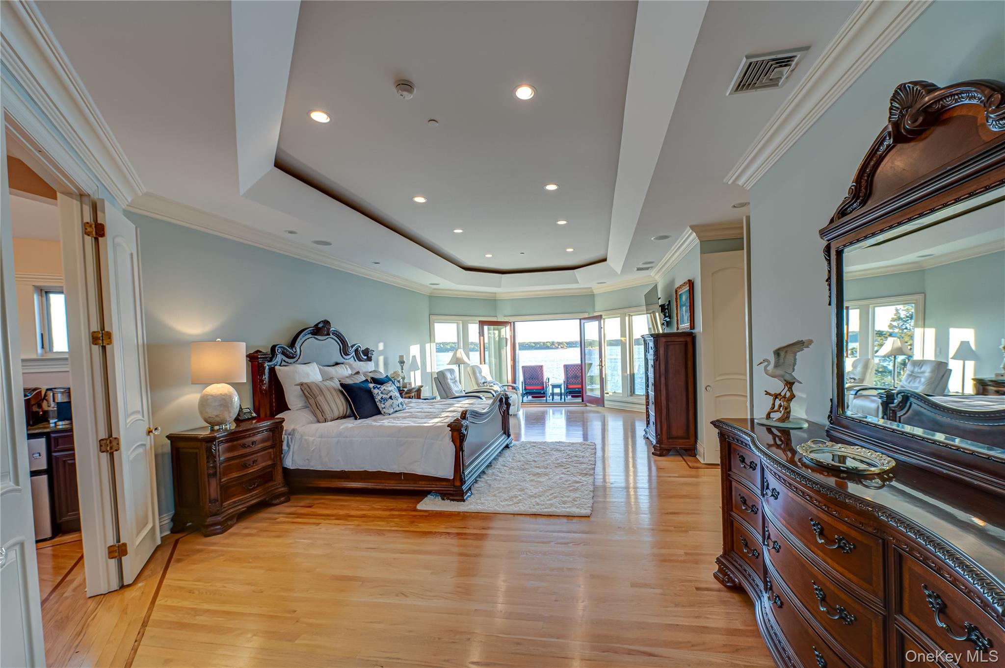Bedroom featuring crown molding, visible vents, light wood-type flooring, recessed lighting, and a tray ceiling