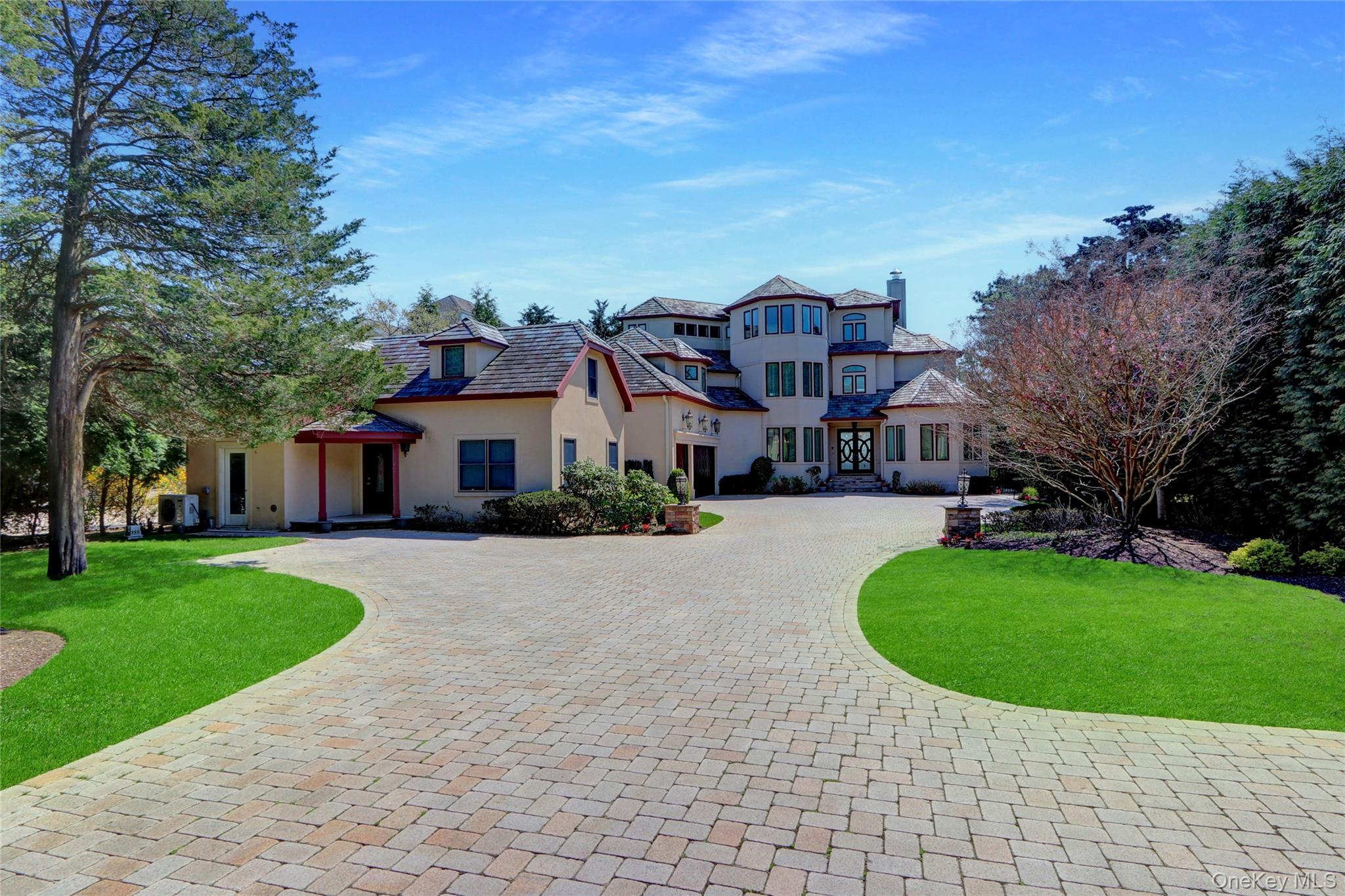 View of front of home featuring a front yard, stucco siding, curved driveway, and a chimney