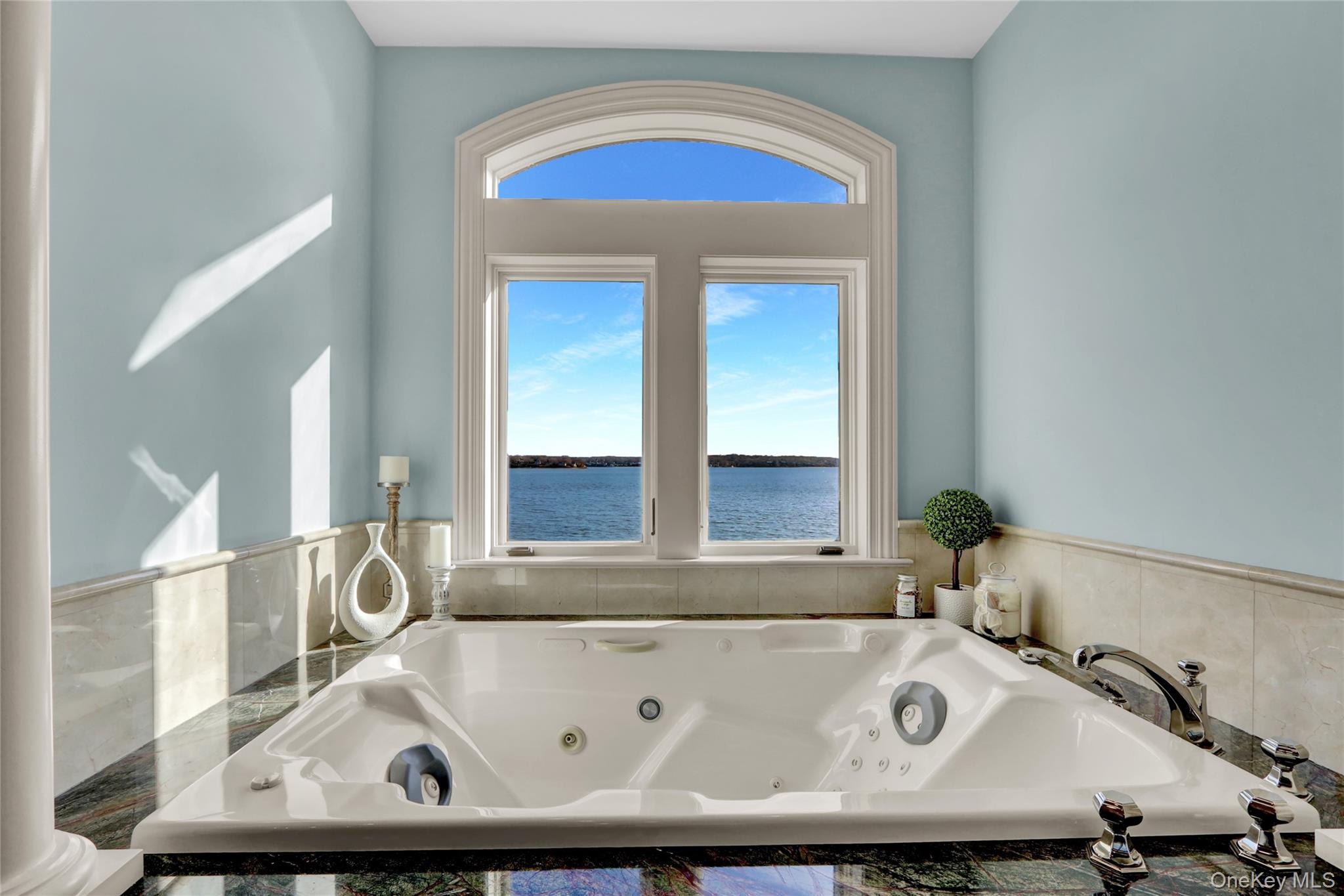 Full bath with a healthy amount of sunlight, a jetted tub, and a water view