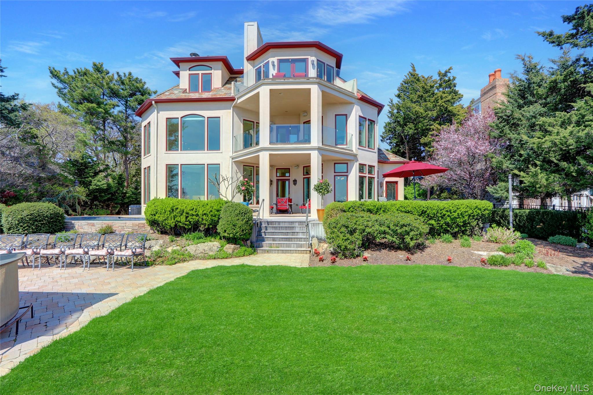 Rear view of house with a balcony, a chimney, covered porch, stucco siding, and a yard