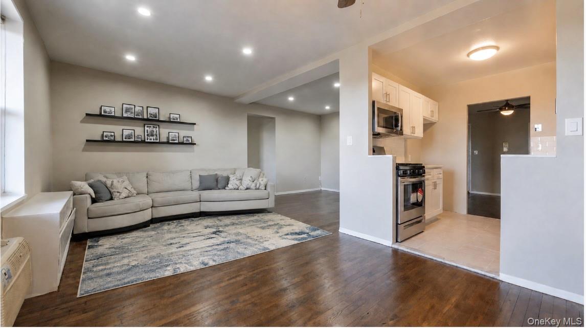 Spacious living room featuring hardwood floors, recessed lighting and a neutral color palette, with an open layout that flows seamlessly into the dining area and kitchen.